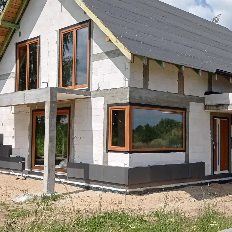 Realizacja — dom z oknem narożnym i drzwiami wejściowymi w kolorze złoty dąb