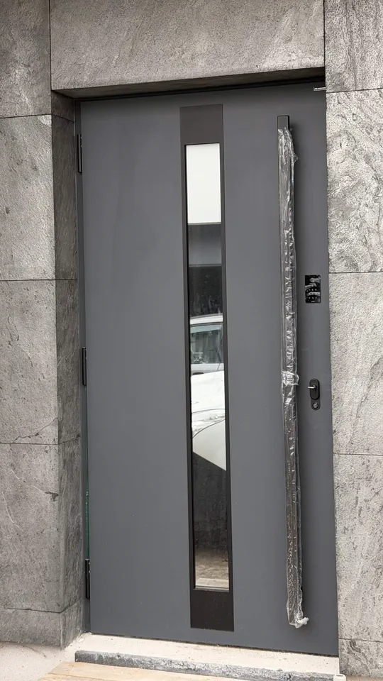 Realizacja — antracytowe drzwi wejściowe w portalu z płyt kamiennych