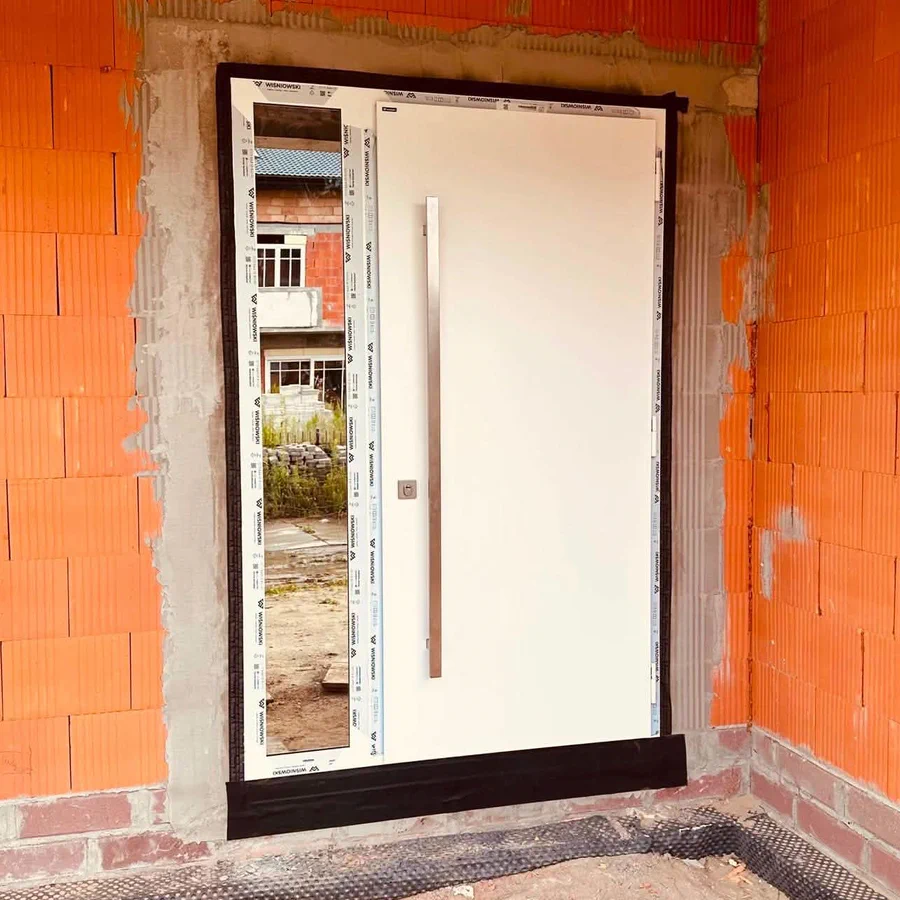 Realizacja — białe drzwi wejściowe z doświetlem w murze z ceramiki